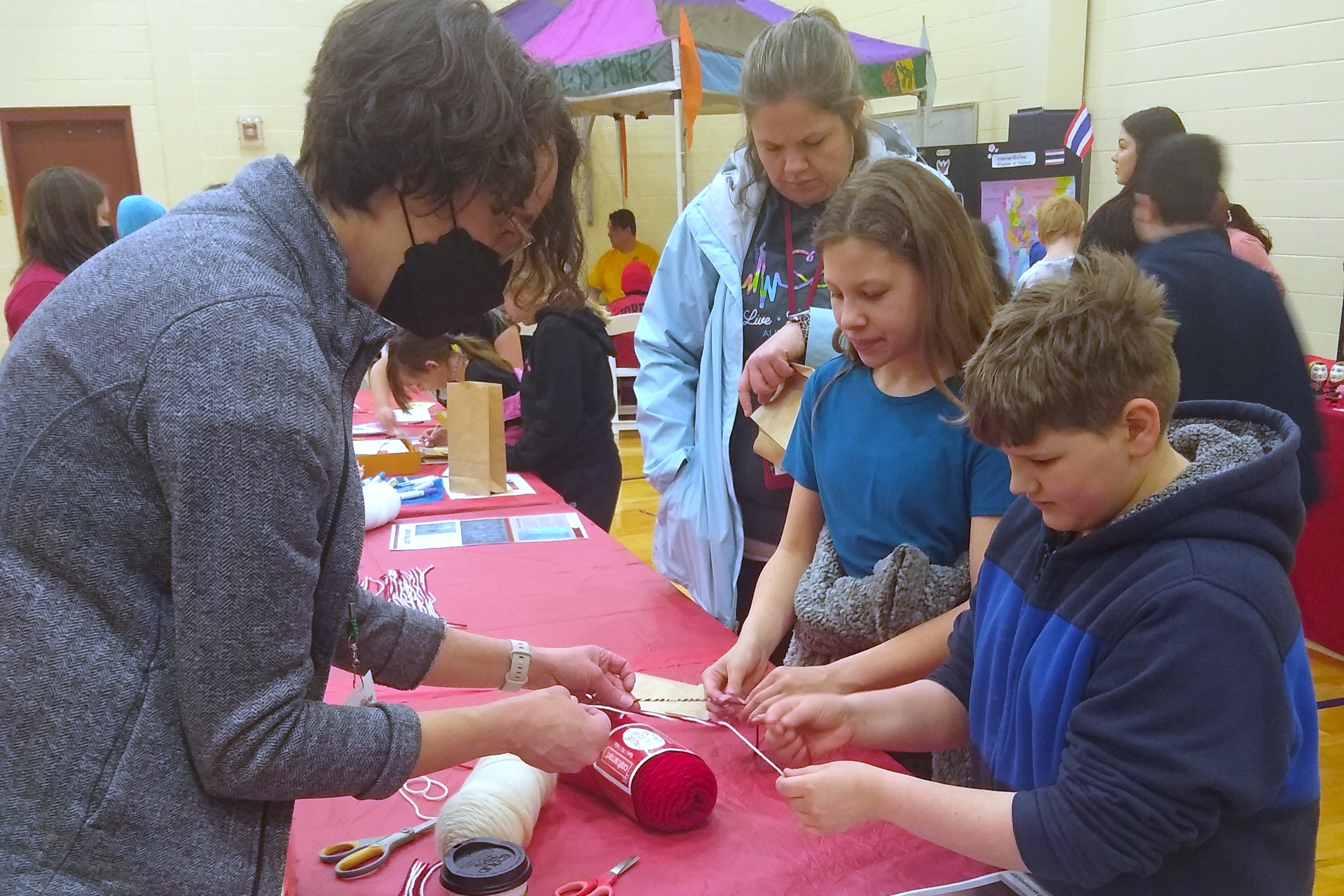 Image of a woman helping two children complete a craft. 