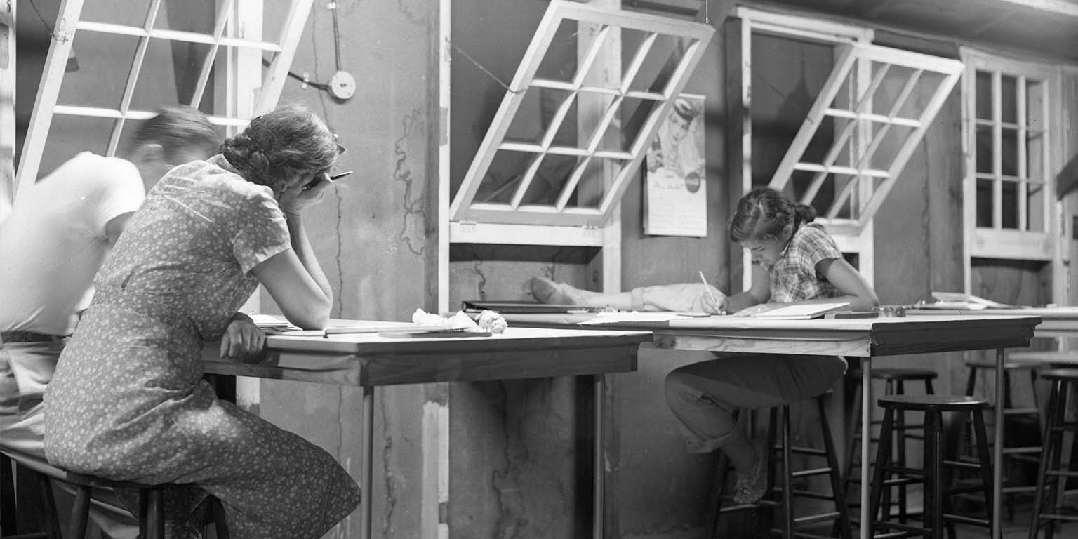 Three individuals sitting at tables looking over and updating records.